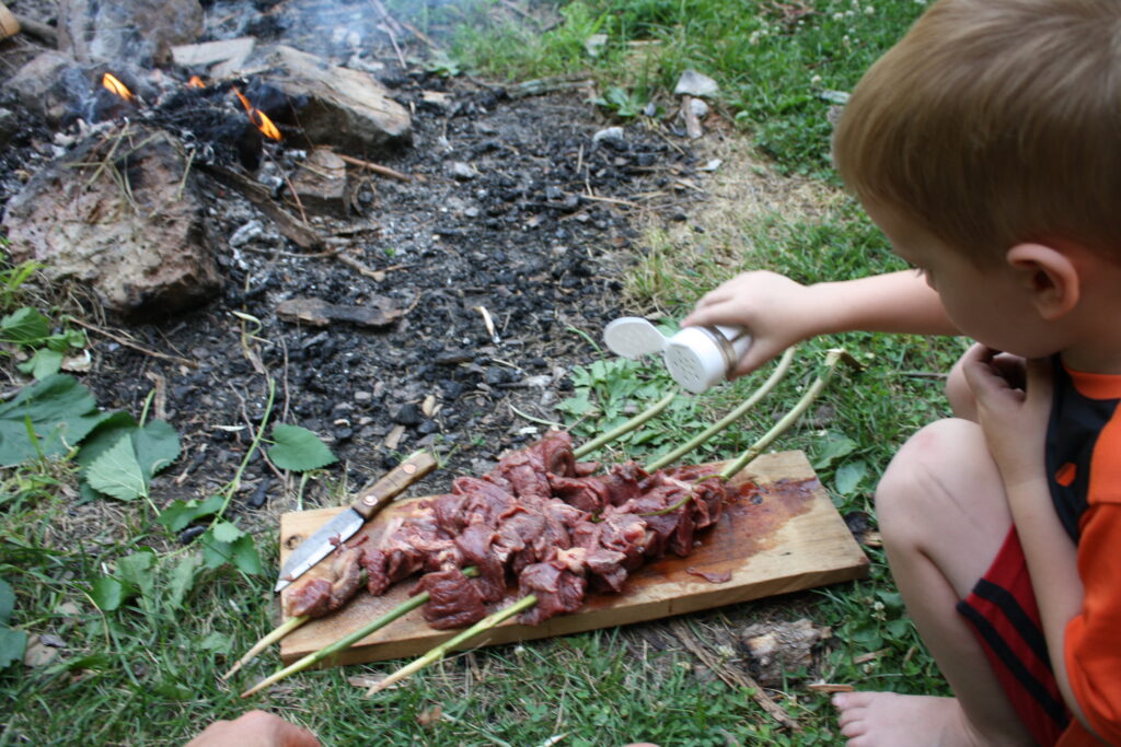 boy seasoning skewered meat