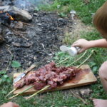 boy seasoning skewered meat