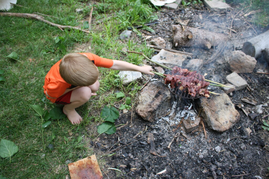 boy tending skewers on a fire