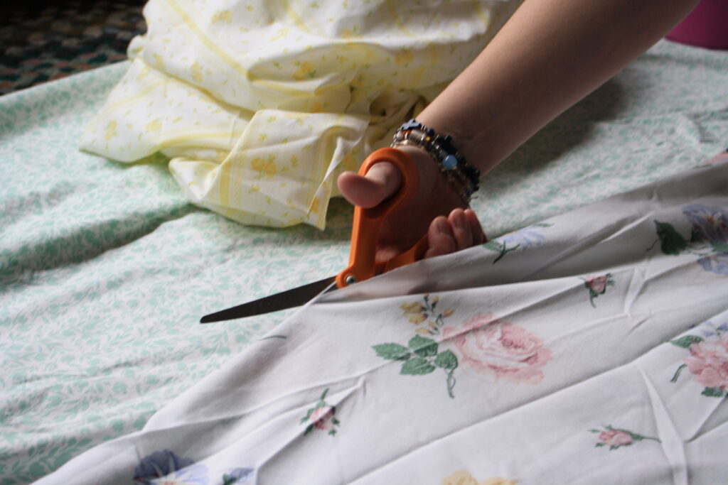 woman's hand cutting fabric with scissors