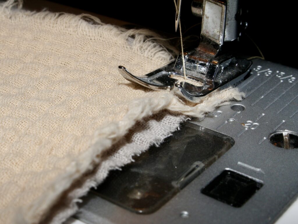 Two layers of muslin cotton being sewn together on sewing machine.