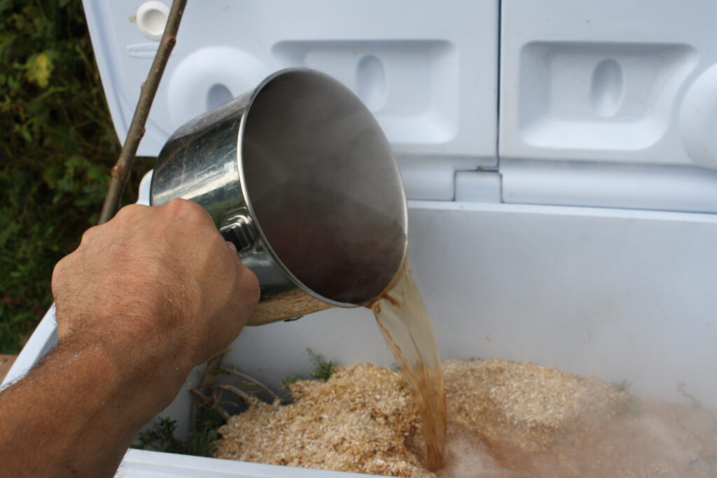 pouring hot juniper water on beer malt