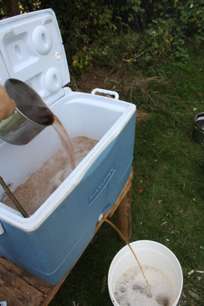 a pot pouring hot juniper water over the mash in the sparging process