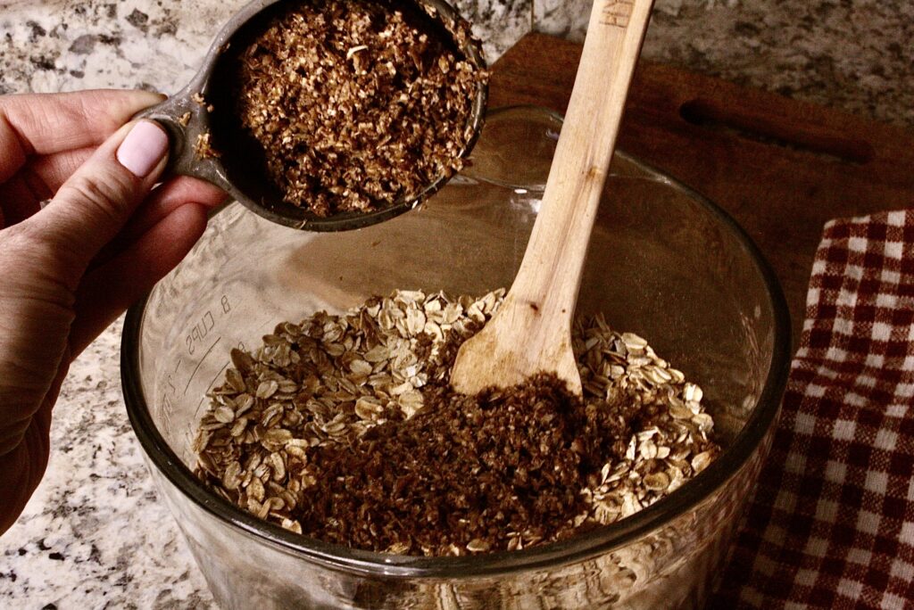 Hand dumping spent grains into mixing bowl