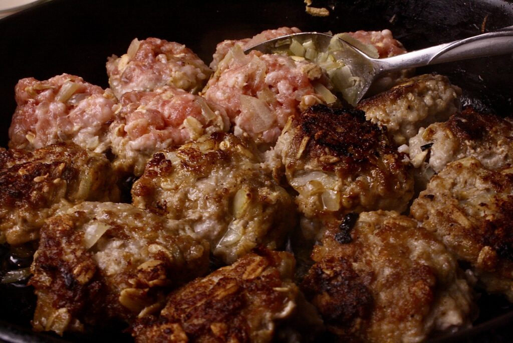 spoon flipping Swedish meatballs over in a pan