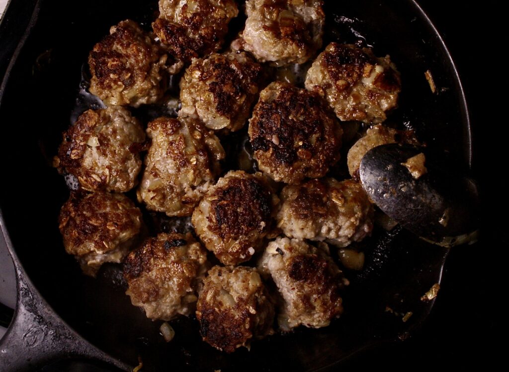 Swedish meatballs cooking in a cast iron skillet