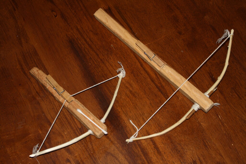 two wooden toy crossbows with a q-tip