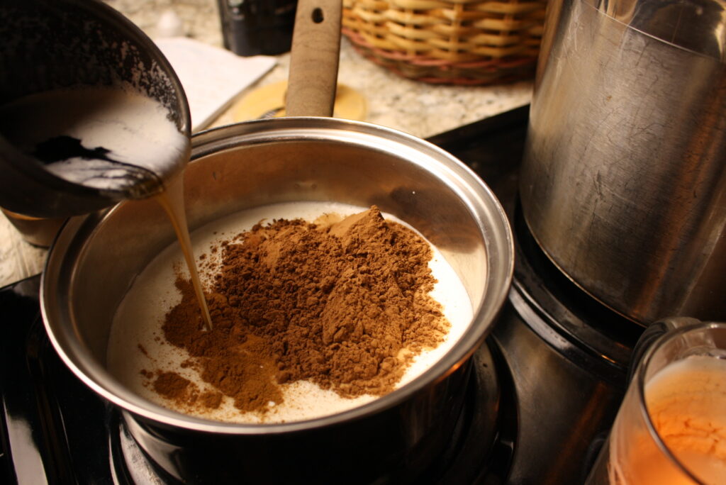 pouring maple syrup into a pan of milk on the stovetop