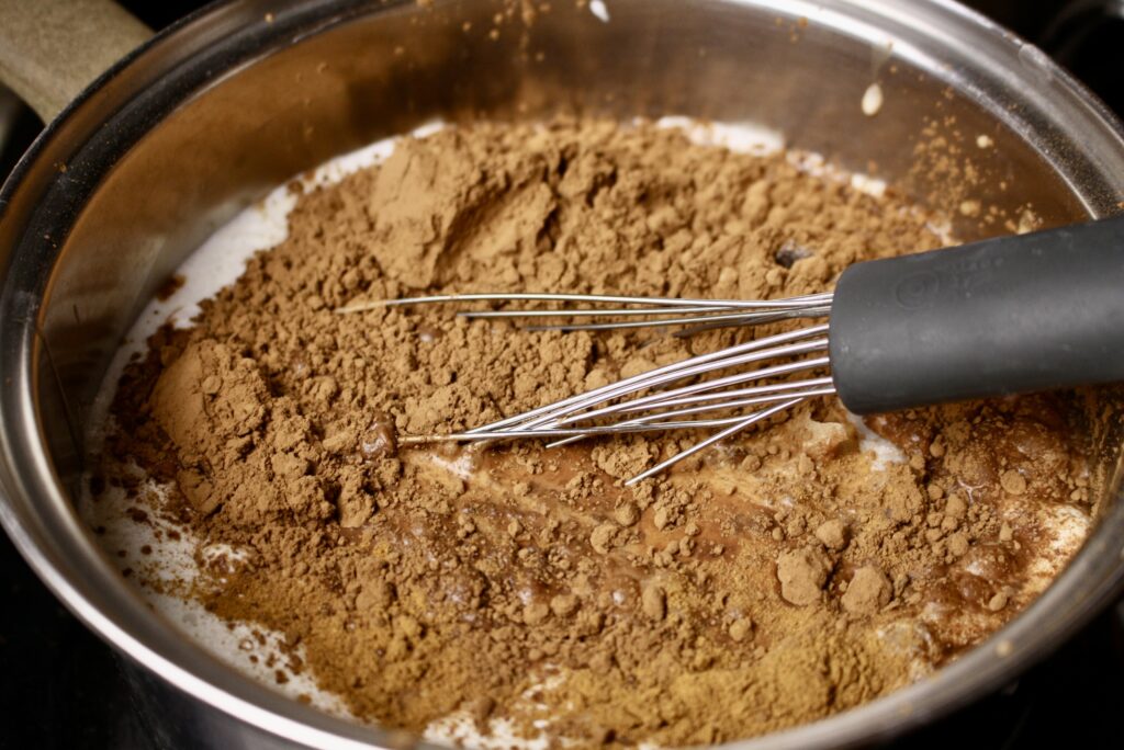 cocoa powder and cinnamon being whisked into milk