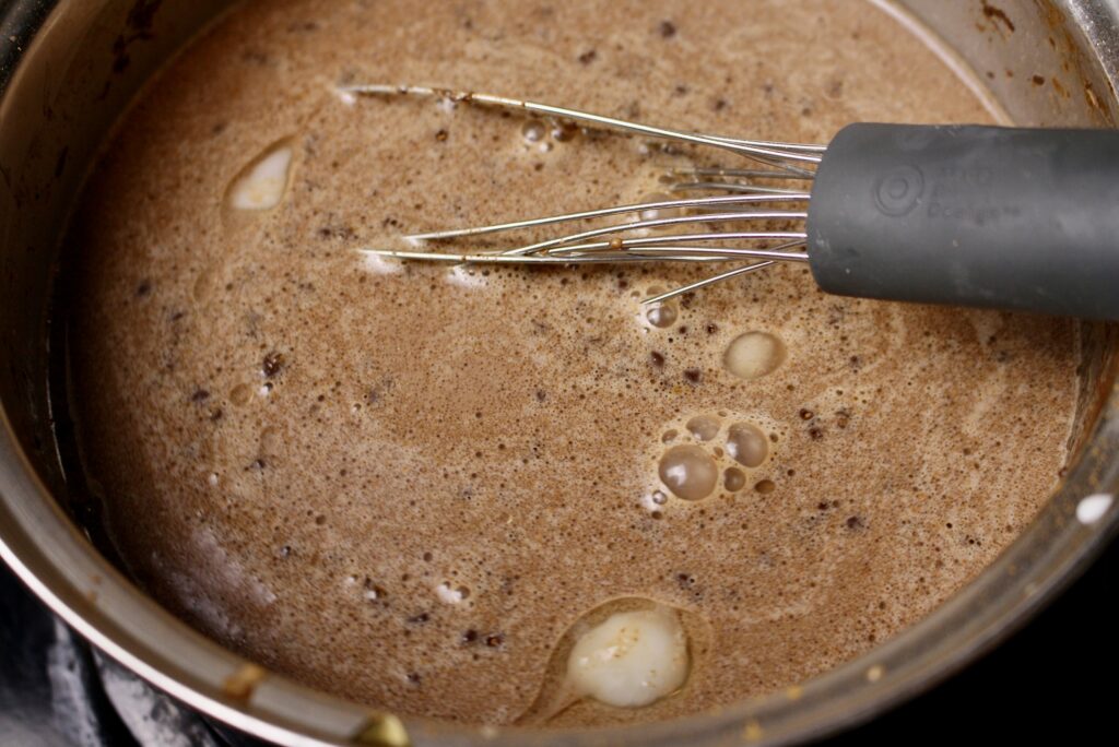 whisk blending hot cocoa ingredients in a pan on stovetop