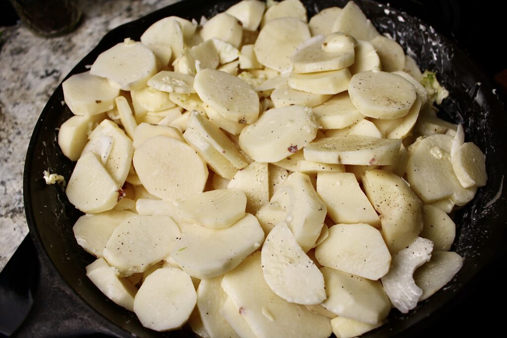 scalloped potatoes with onions and garlic in a cast iron skillet