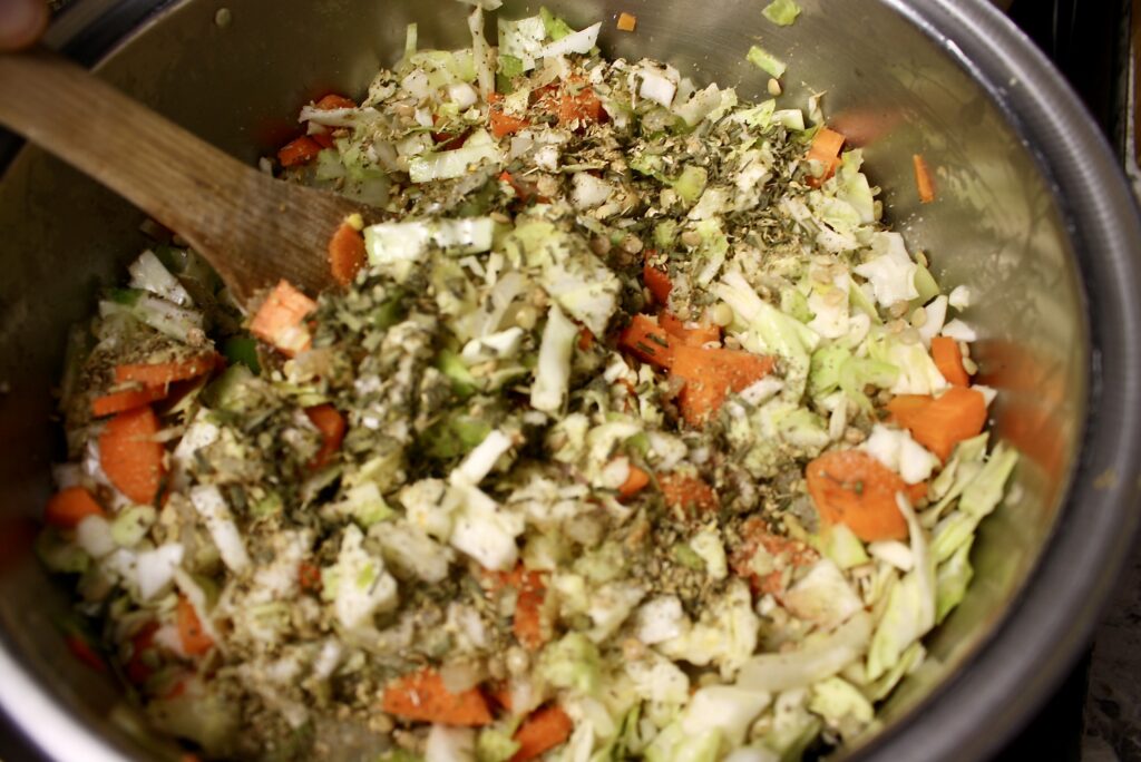 wooden spoon stirring veggies and lentils in a pot