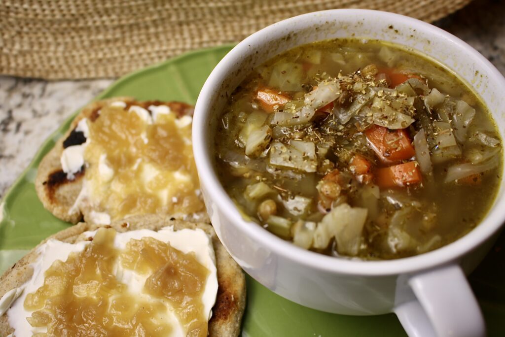 cabbage and lentil soup in a bowl next to flatbread on a plate