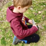 boy in a red sweater whittling a stick with a knife