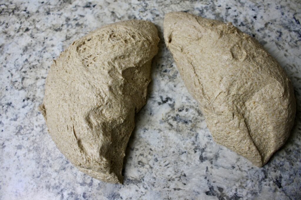 ball of dough cut in half on a countertop