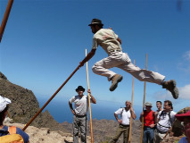 a photo of a man from the Canary Islands leaping with a long shepherd's stick