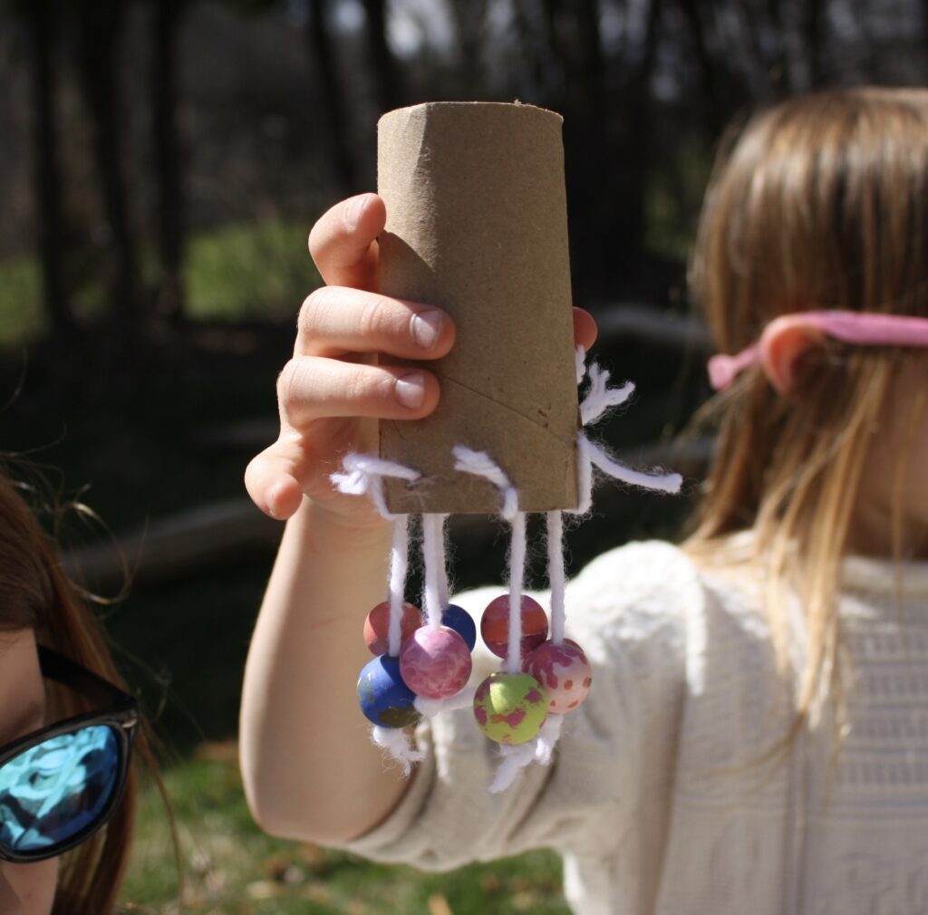 girl holding wooden bead jellyfish craft