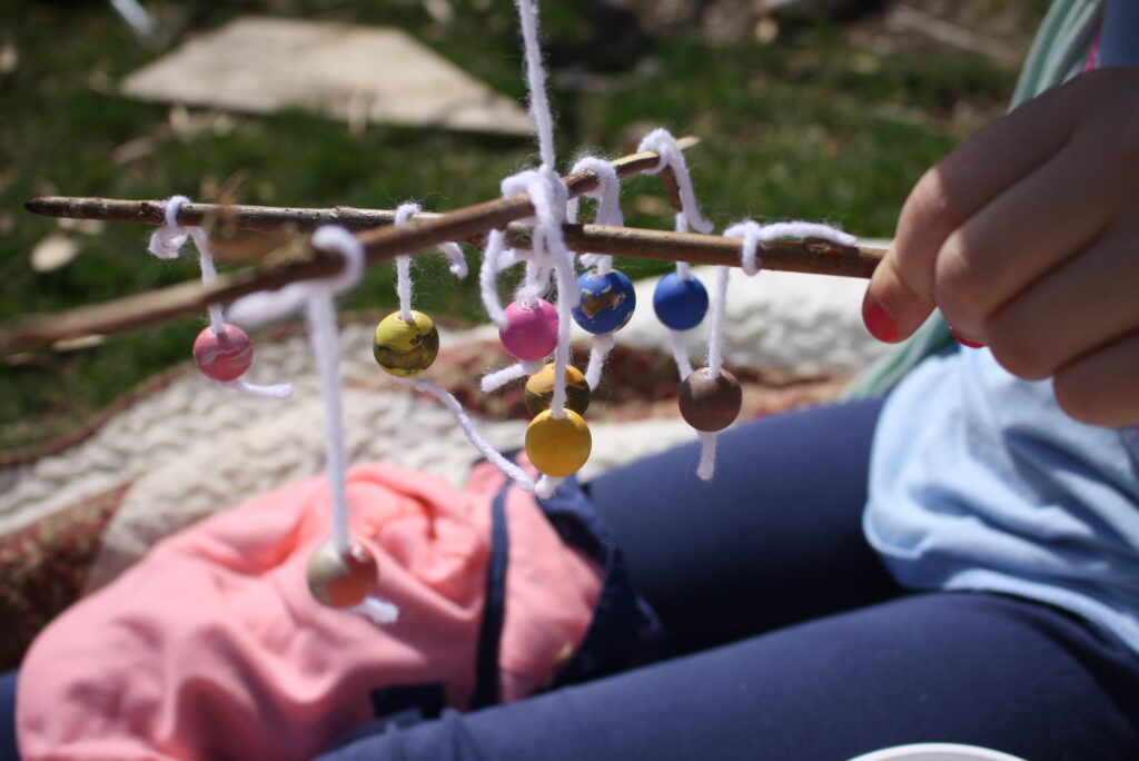 hand holding wooden sicks with wooden beads tied to them