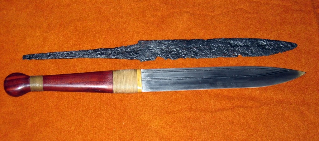 An artifact of a germanic scramaseax next to a replica scramaseax