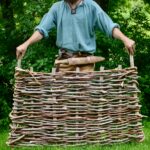 photo of a man holding a woven fence panel.