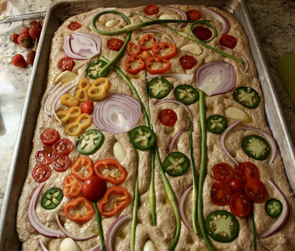 summer sourdough focaccia on a sheet pan with flower designs made of veggies