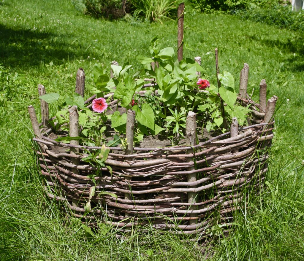 a circular planter made from wicker with pick flowers