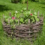 a circular planter made from wicker with pick flowers