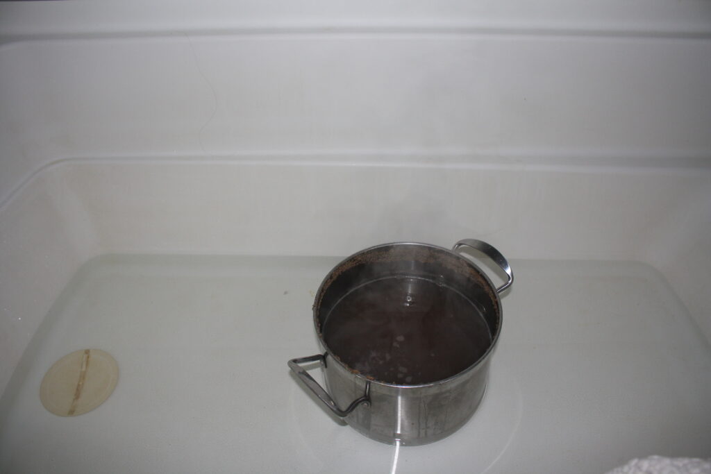 beer wort in a metal pot sitting in a bathtub of water to cool