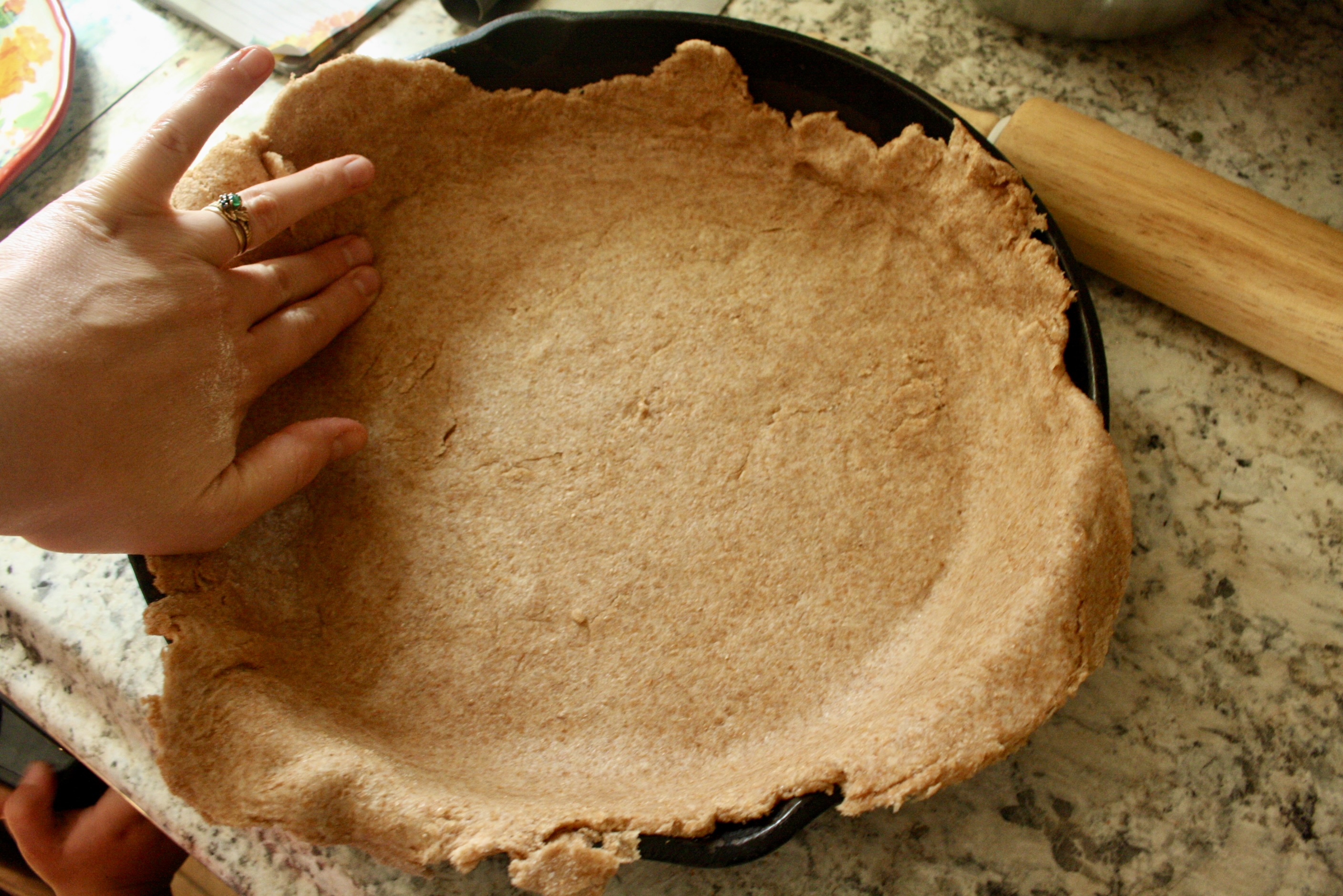 hand placing dough in skillet