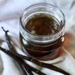 vanilla simple syrup in a jar next to vanilla beans