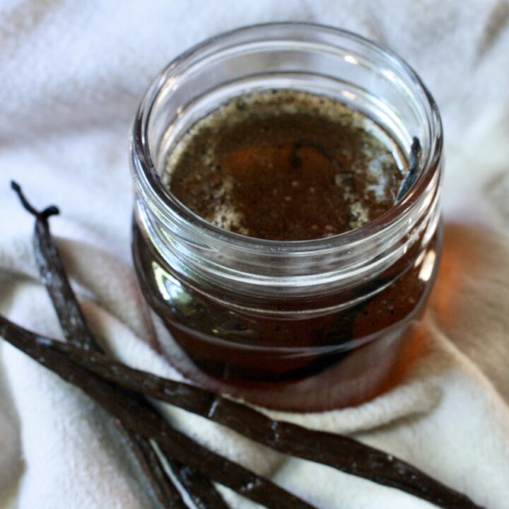 vanilla simple syrup in a jar next to vanilla beans