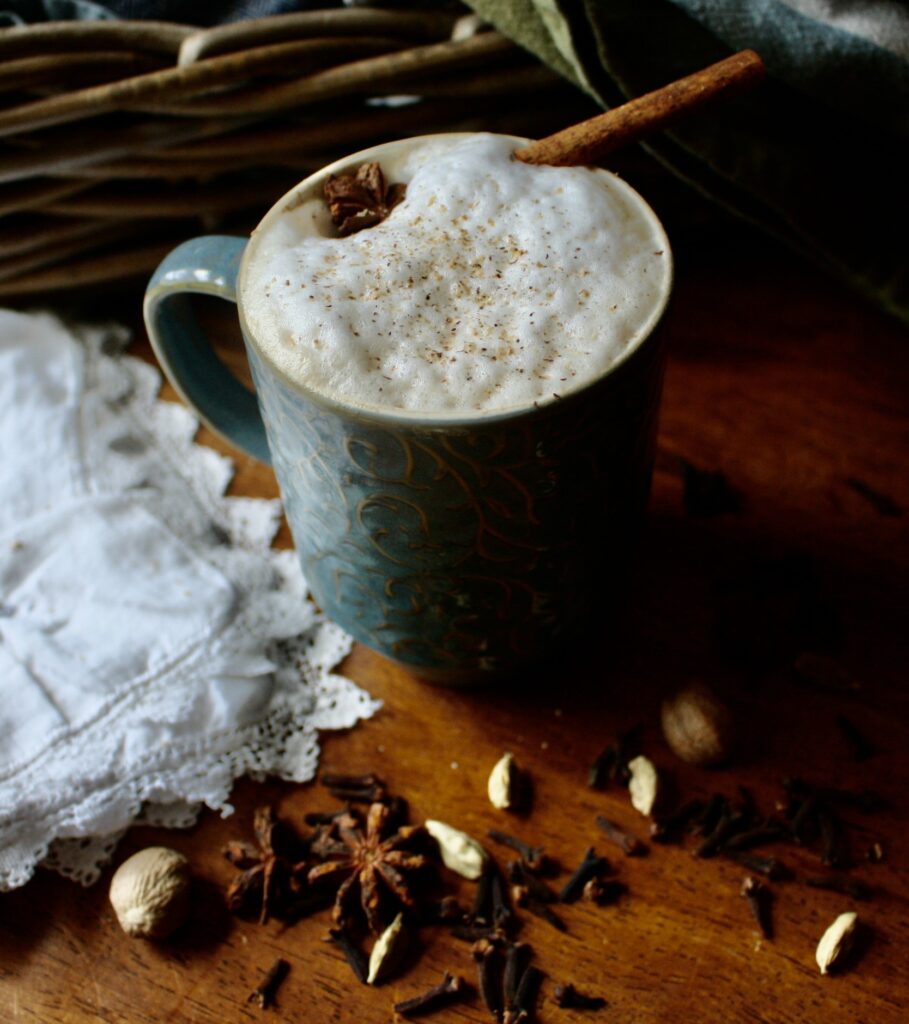 mug with a chai latte sitting on a table with spices