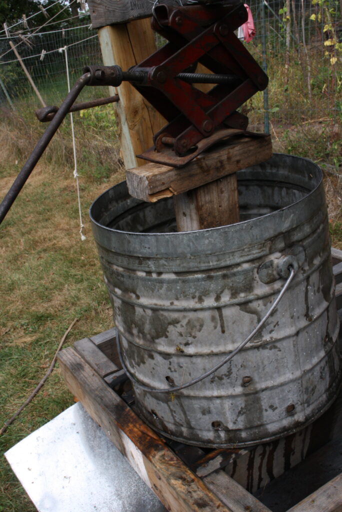 a car jack being used as a press for a homemade apple cider press