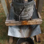 an apple press with juice running into a pot