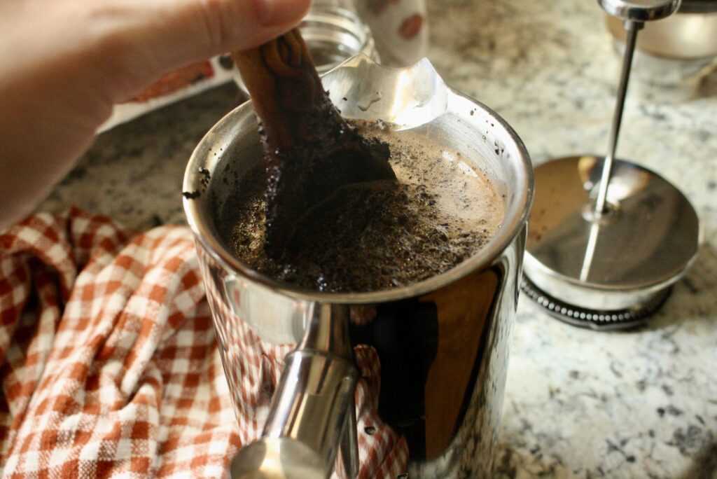 hand stirring coffee with a wooden spoon