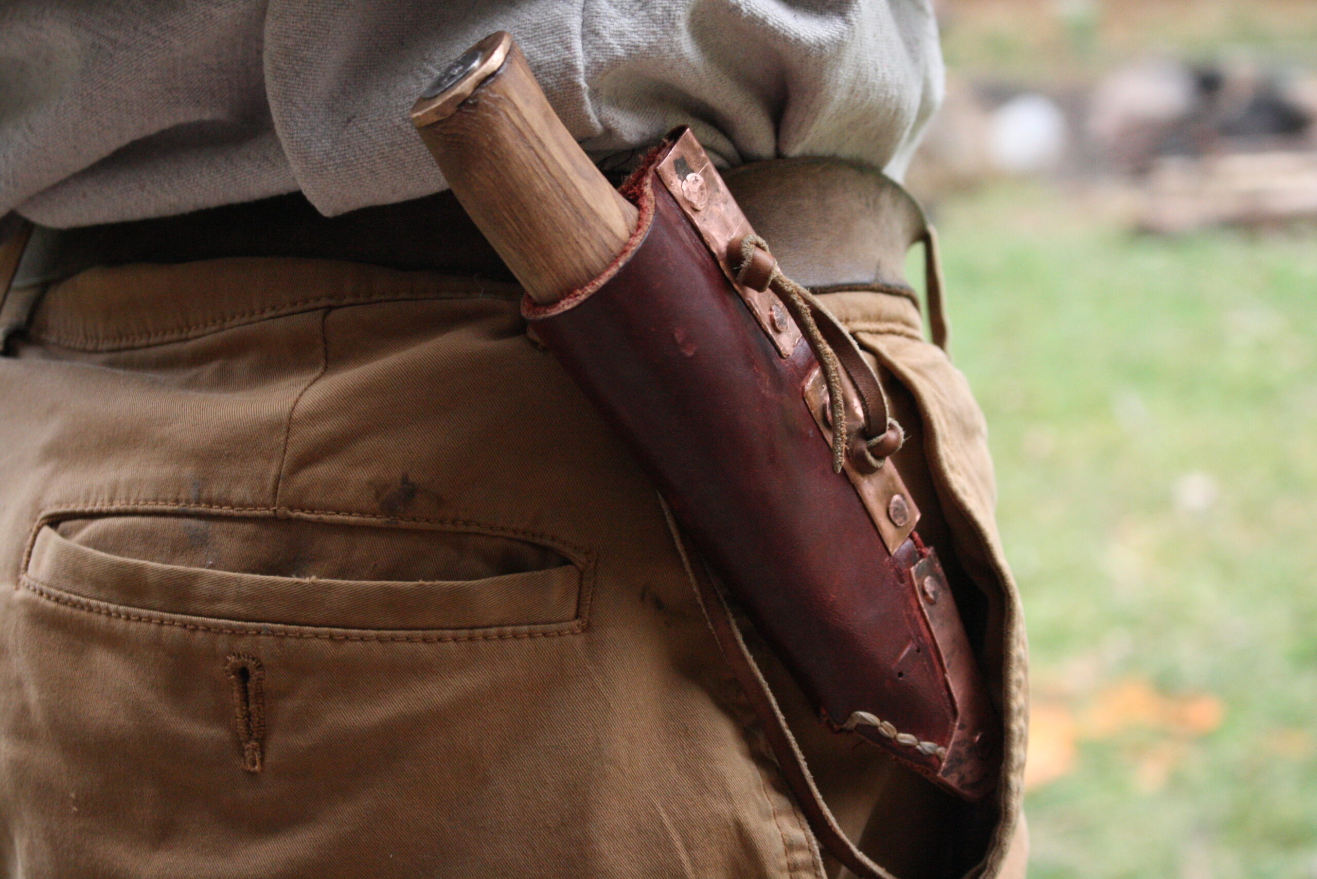 knife in leather and copper sheath suspended horizontally at the waste from a leather belt