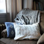 cream colored sweater pillow sitting on a brown chair