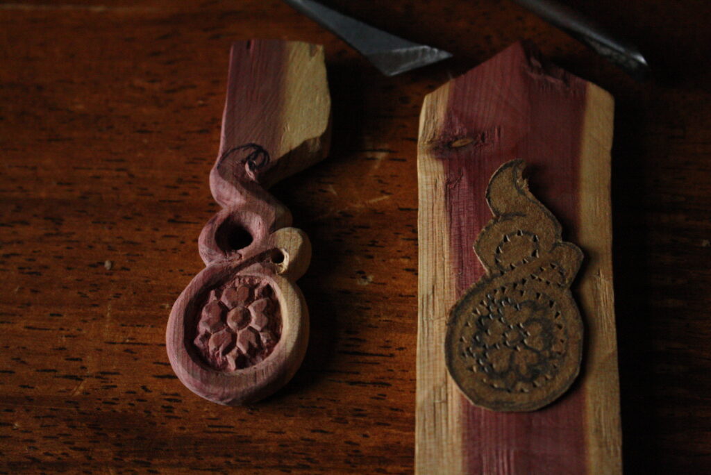 A wooden earring and a cardboard template sitting on a slab of wood