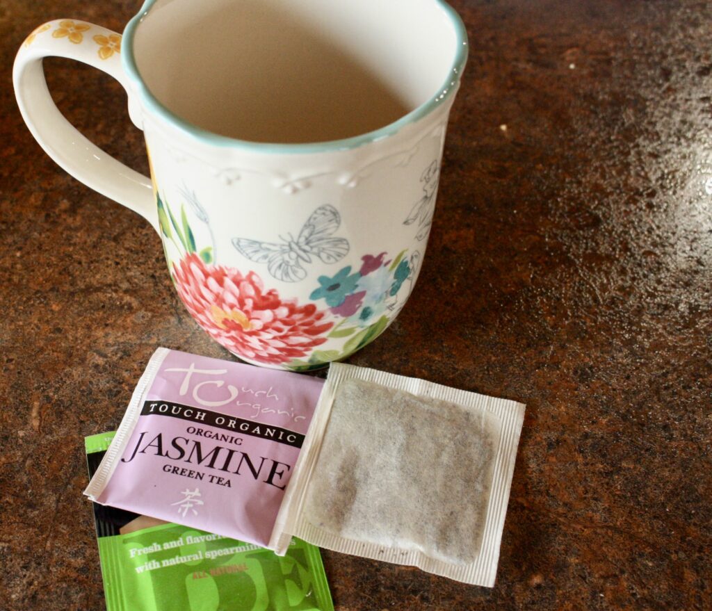 coffee mug sitting on a counter with three tea bags next to it