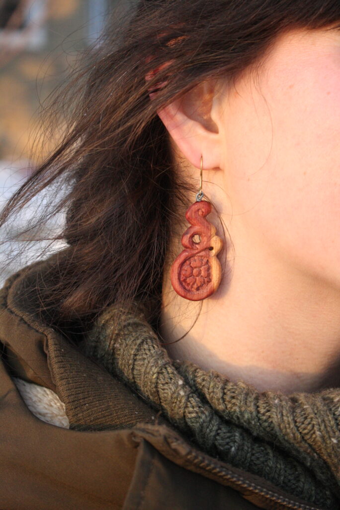 wooden folk art earring hanging from a woman's ear