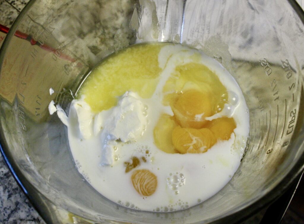 eggs, yogurt, milk, and melted butter in a glass mixing bowl