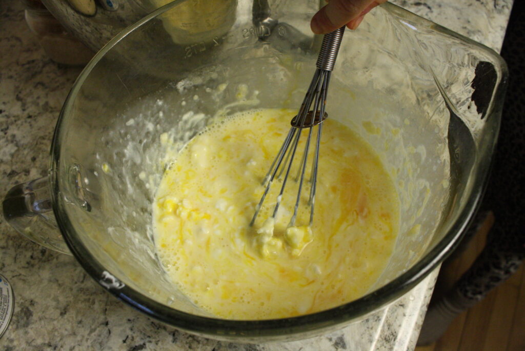 a whisk stirring ingredients in a glass mixing bowl