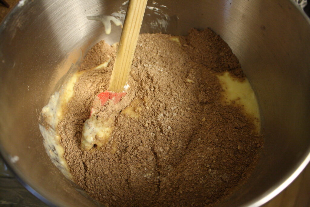 a spatula stirring ingredients for oat flour brownies in a metal bowl