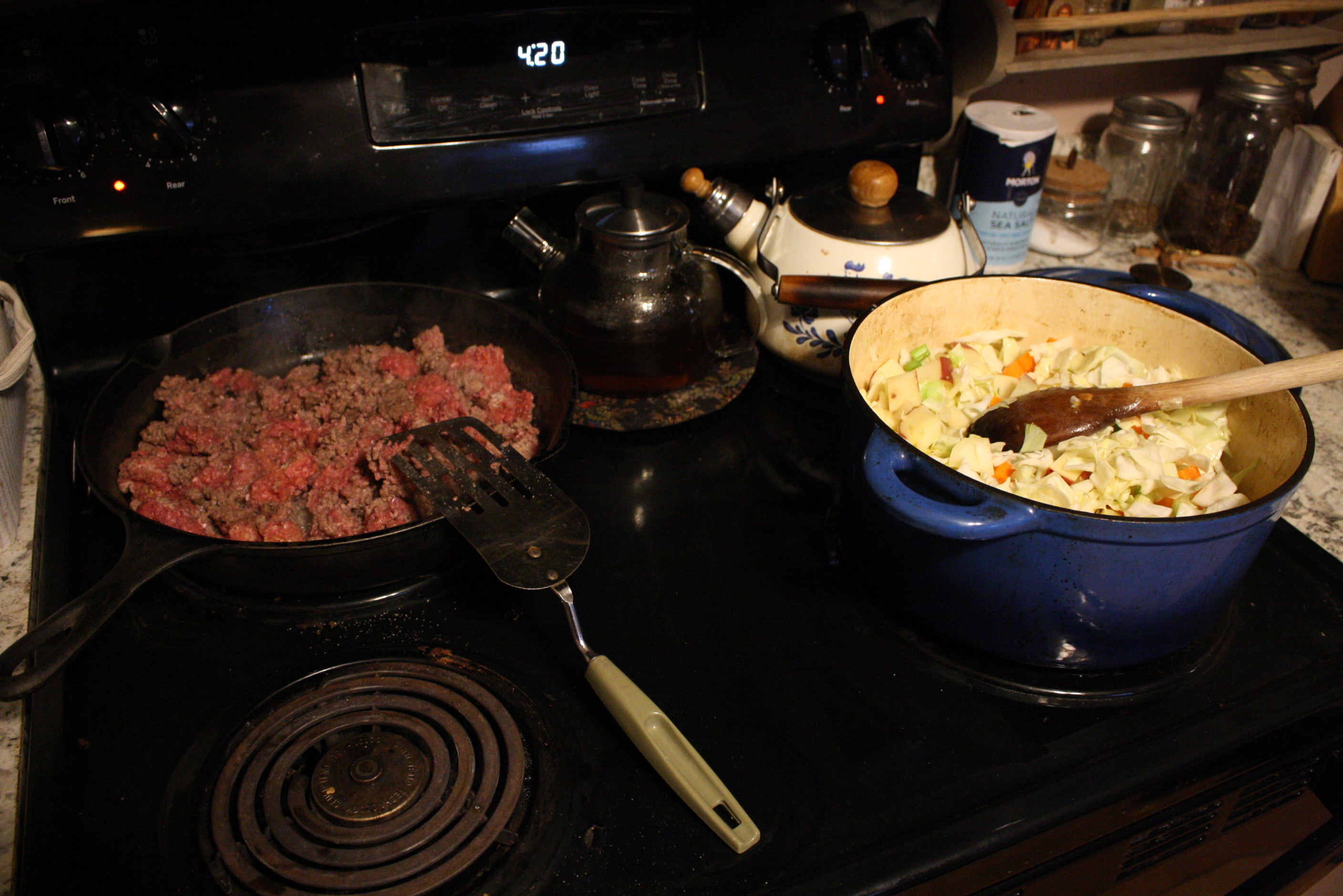 ground beef cooking in a cast iron pan and veggies cooking in a dutch oven