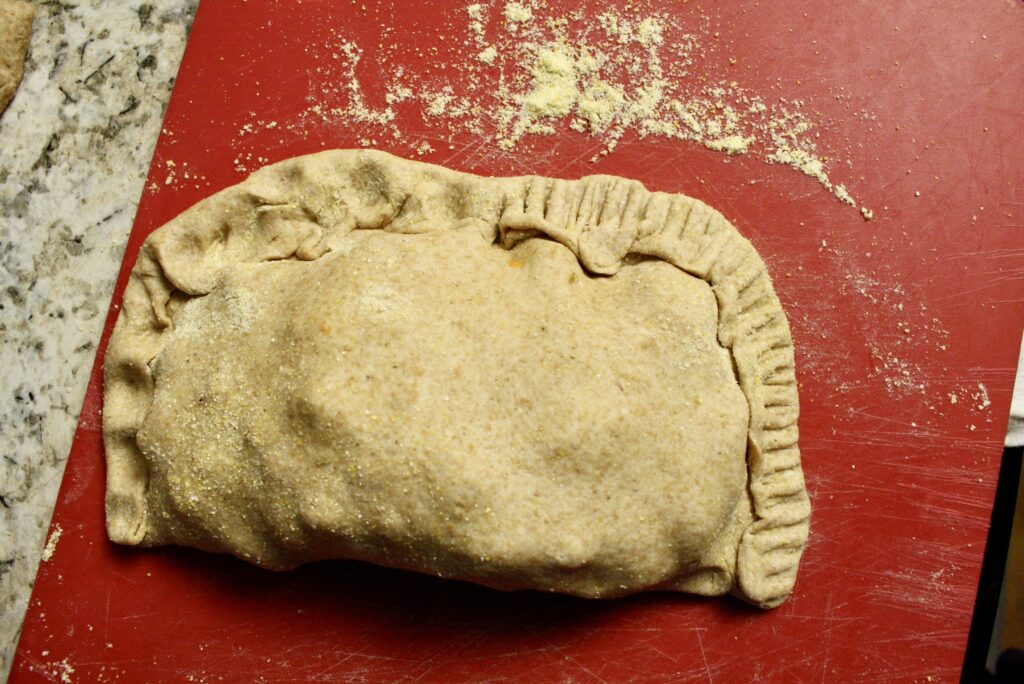 uncooked pasty sealed half with a fork, half pinched