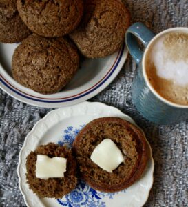 spiced applesauce muffins sitting on a plate next to a cup of coffee and another plate of muffins