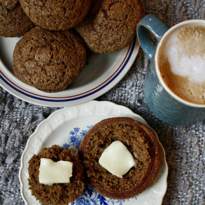 spiced applesauce muffins sitting on a plate next to a cup of coffee and another plate of muffins