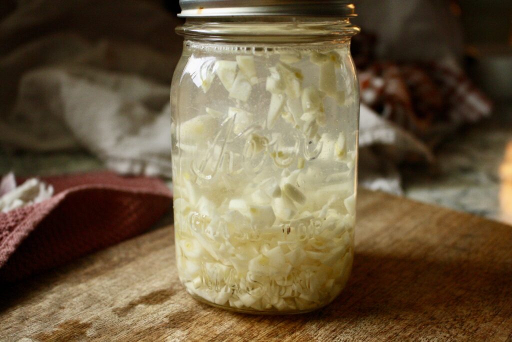 garlic tincture in a pint jar sitting on a cutting board