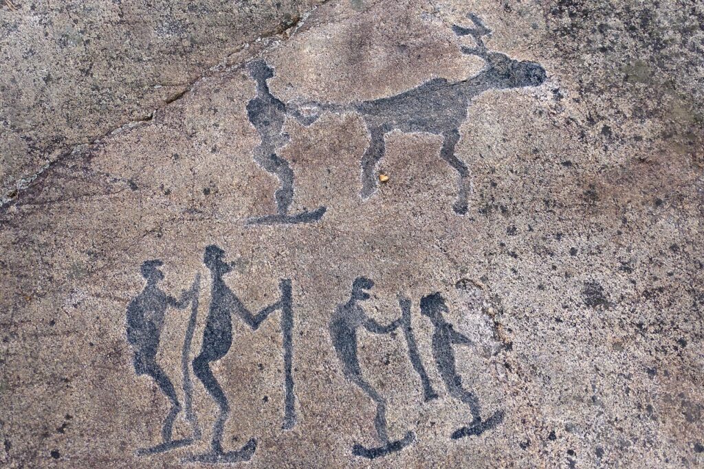 Stone Age carving of people on skis with a moose