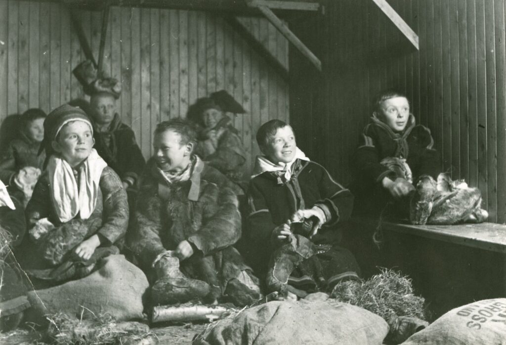 black and white photo of Sami children stuffing their shoes with hay